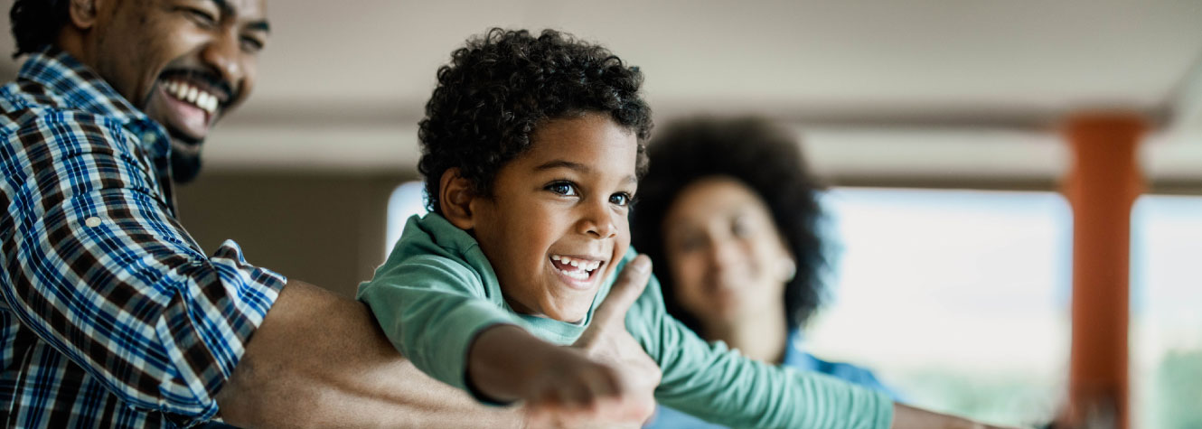 A young boy being lifted in the air by his father.