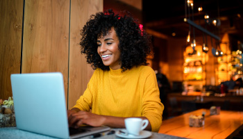 A young woman sitting in a cafe using a laptop.