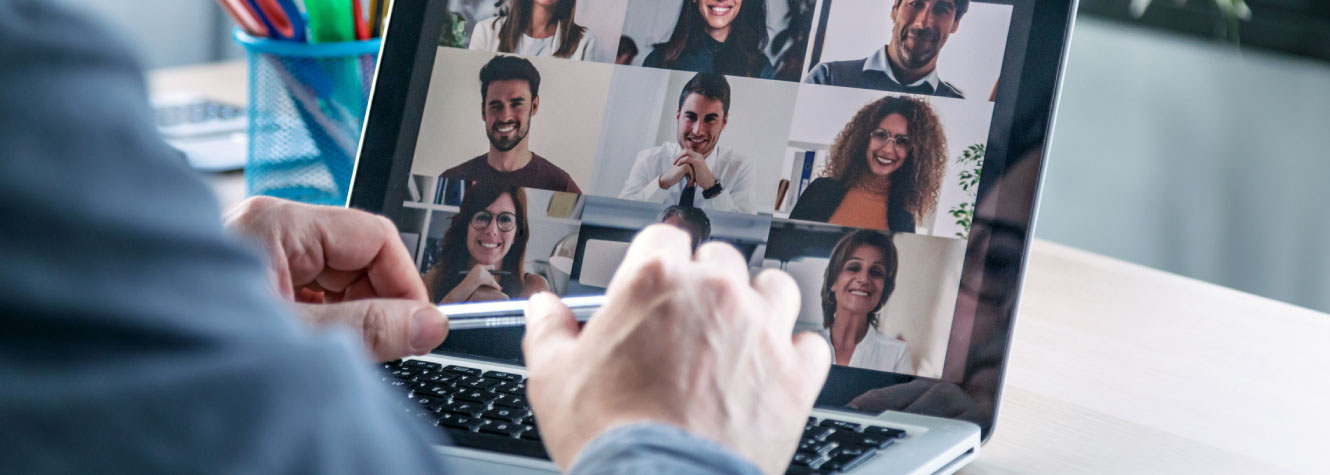 Close up of a person's hands over a laptop. The laptop screen is showing a video conference.