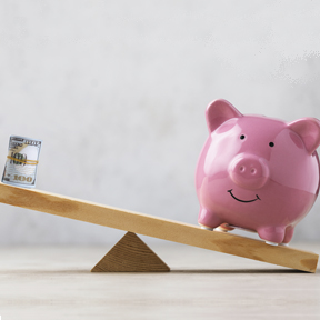 piggy bank on balance beam with roll of $100 gills