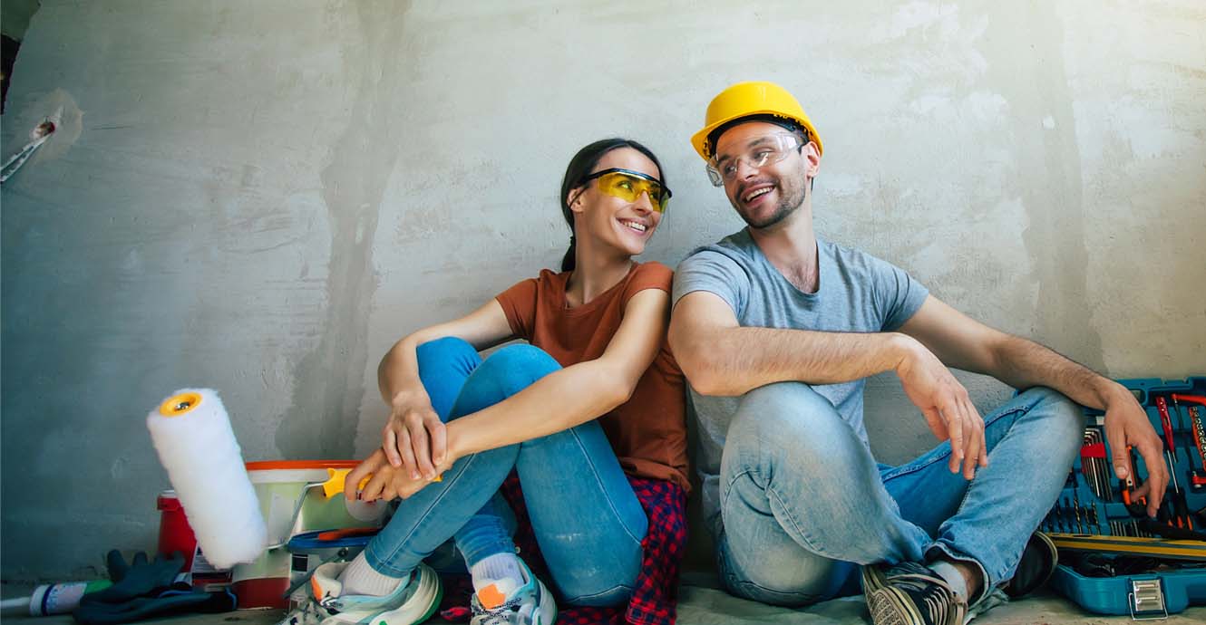couple sitting on floor with paint and tools