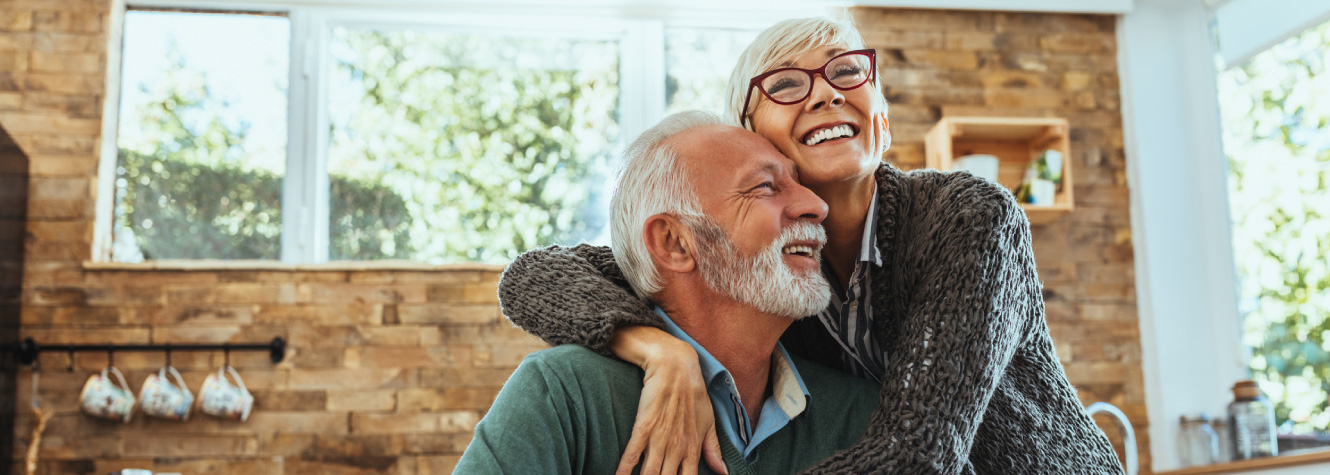 An older couple embracing in a kitchen.