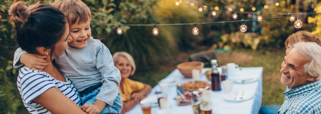 A multi-generational family around a picnic table outside.