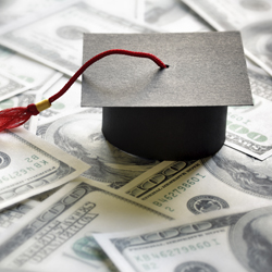 graduation cap sitting on hundred dollar bills